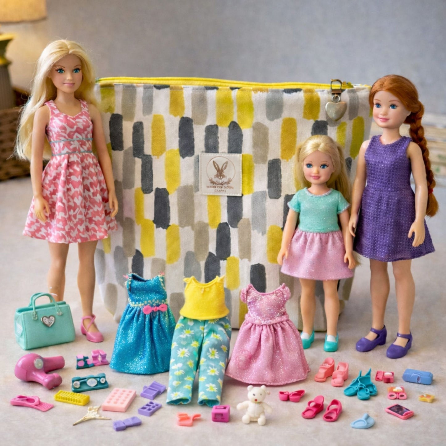 Barbie dolls with various outfits and accessories in front of a patterned bag.